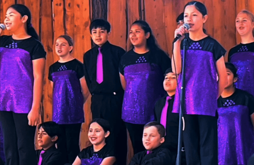 Children's choir performing in purple outfits.
